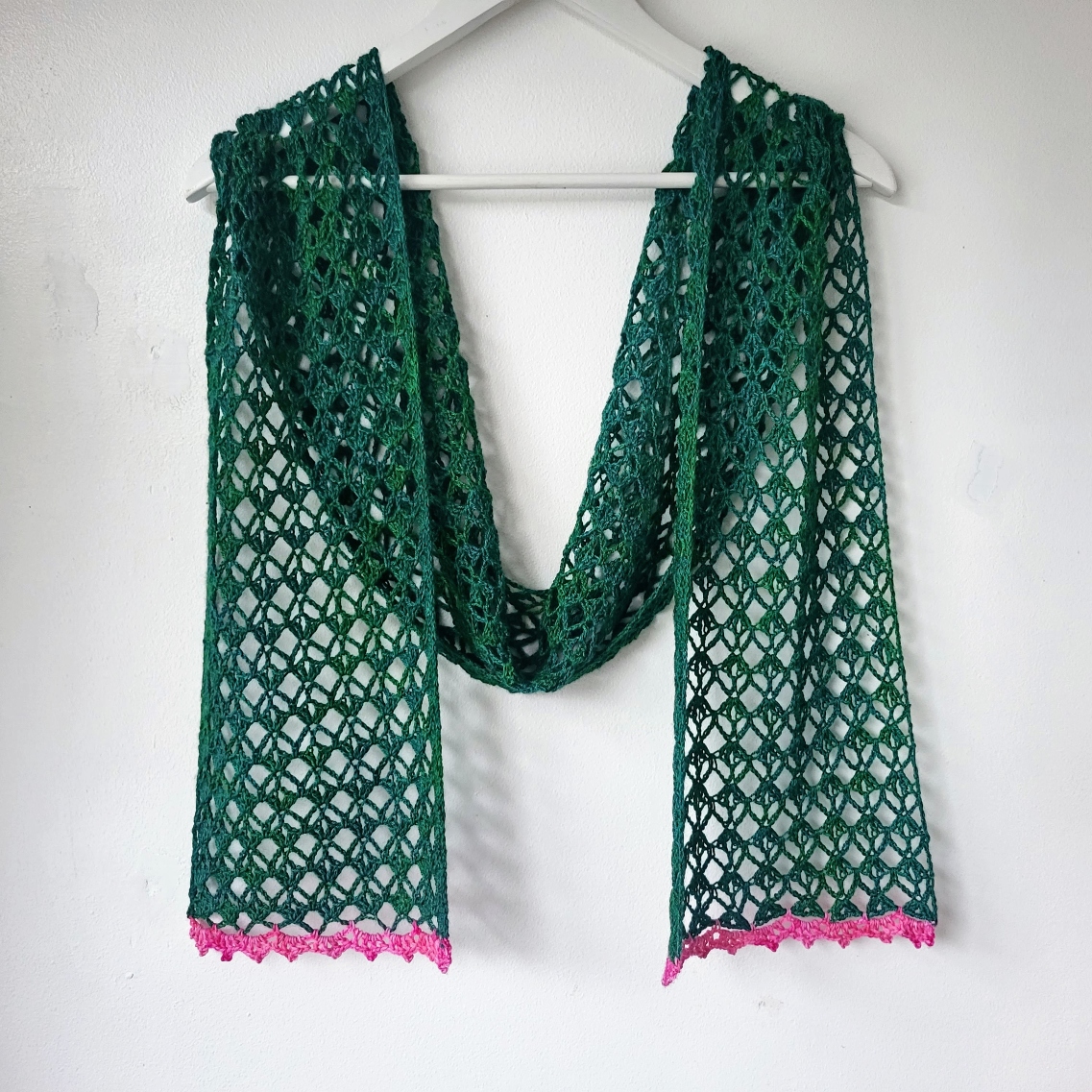 green crochet lace scarf hanging on a wall