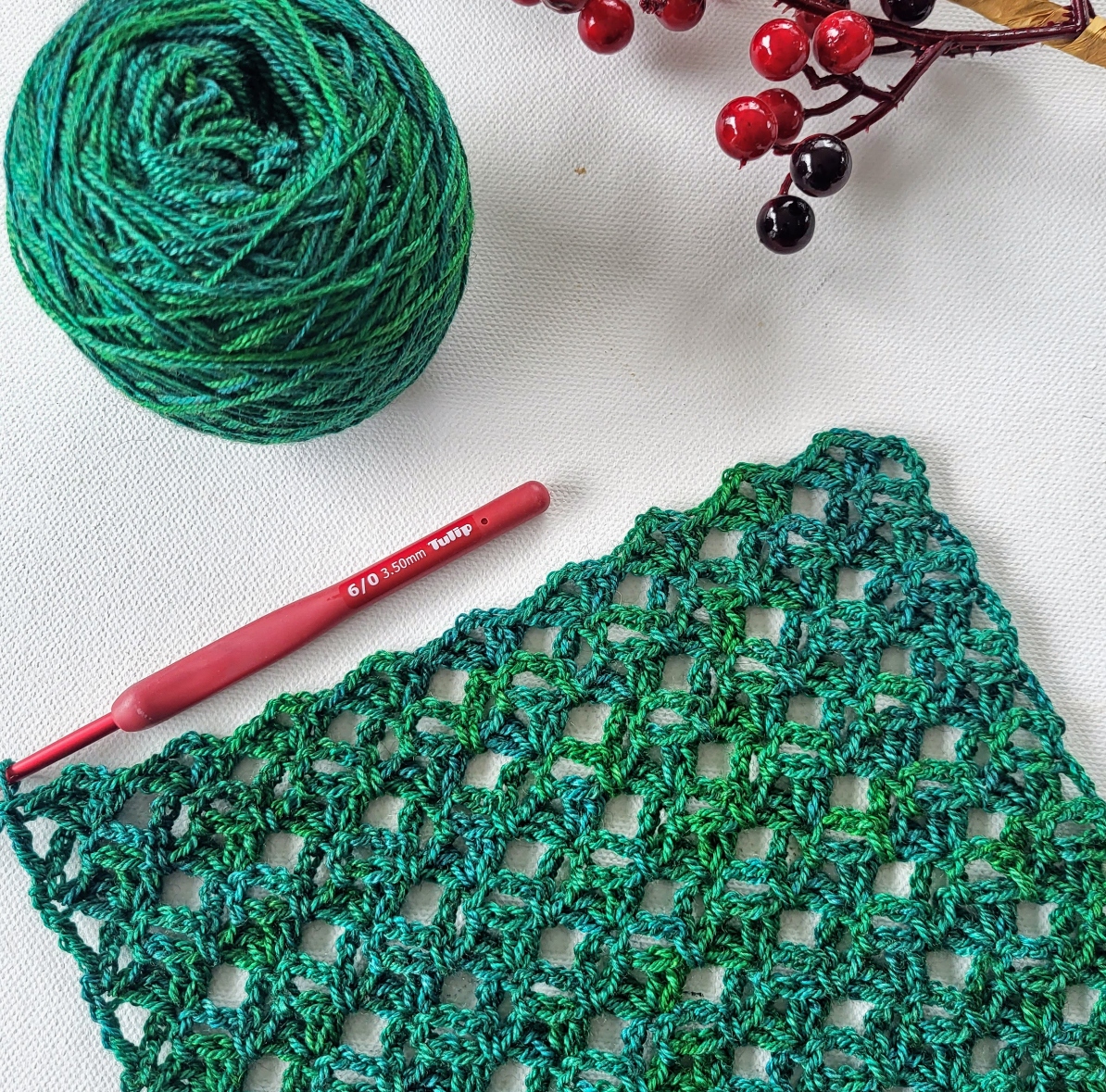 a green piece of crochet and a ball of yarn