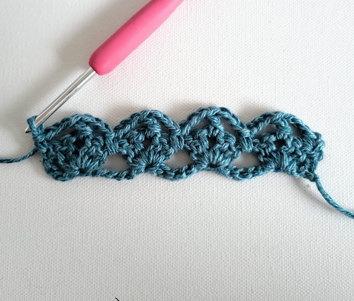 row 2 of a crochet sample and a pink hook