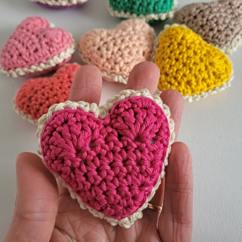 a hand holding a crochet heart