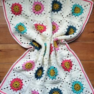 crochet daisy square babt blanket crumpled on a wood floor