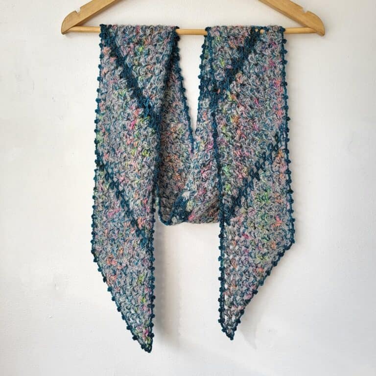 Delicate crochet scarf with a picot edge, made in variegated yarn and displayed on a hanger.