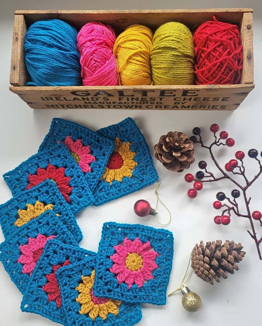 a box of yarn balls and colorful granny squares used to make this pattern