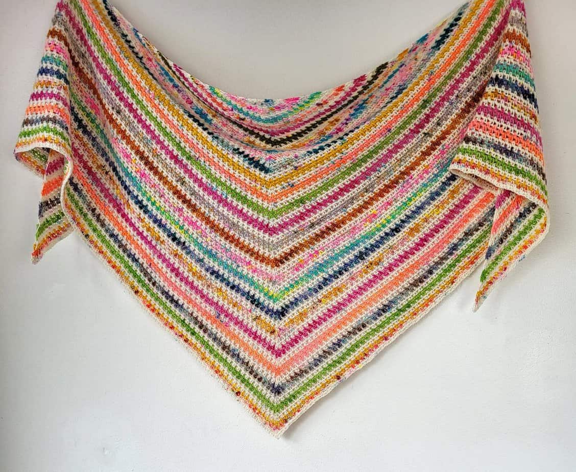 crochet moss stitch triangle shawl hanging on a wall