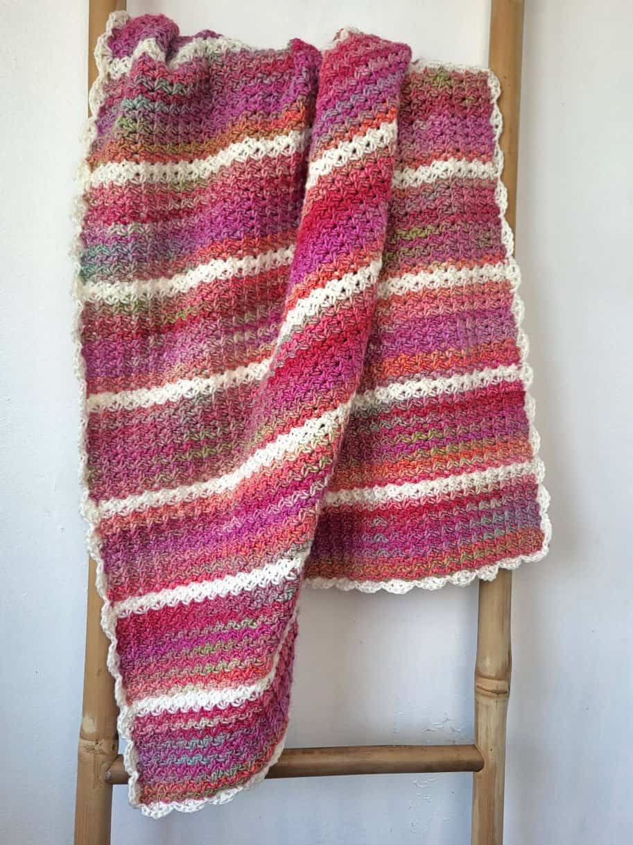 The Pink Drift blanket displayed on a bamboo ladder