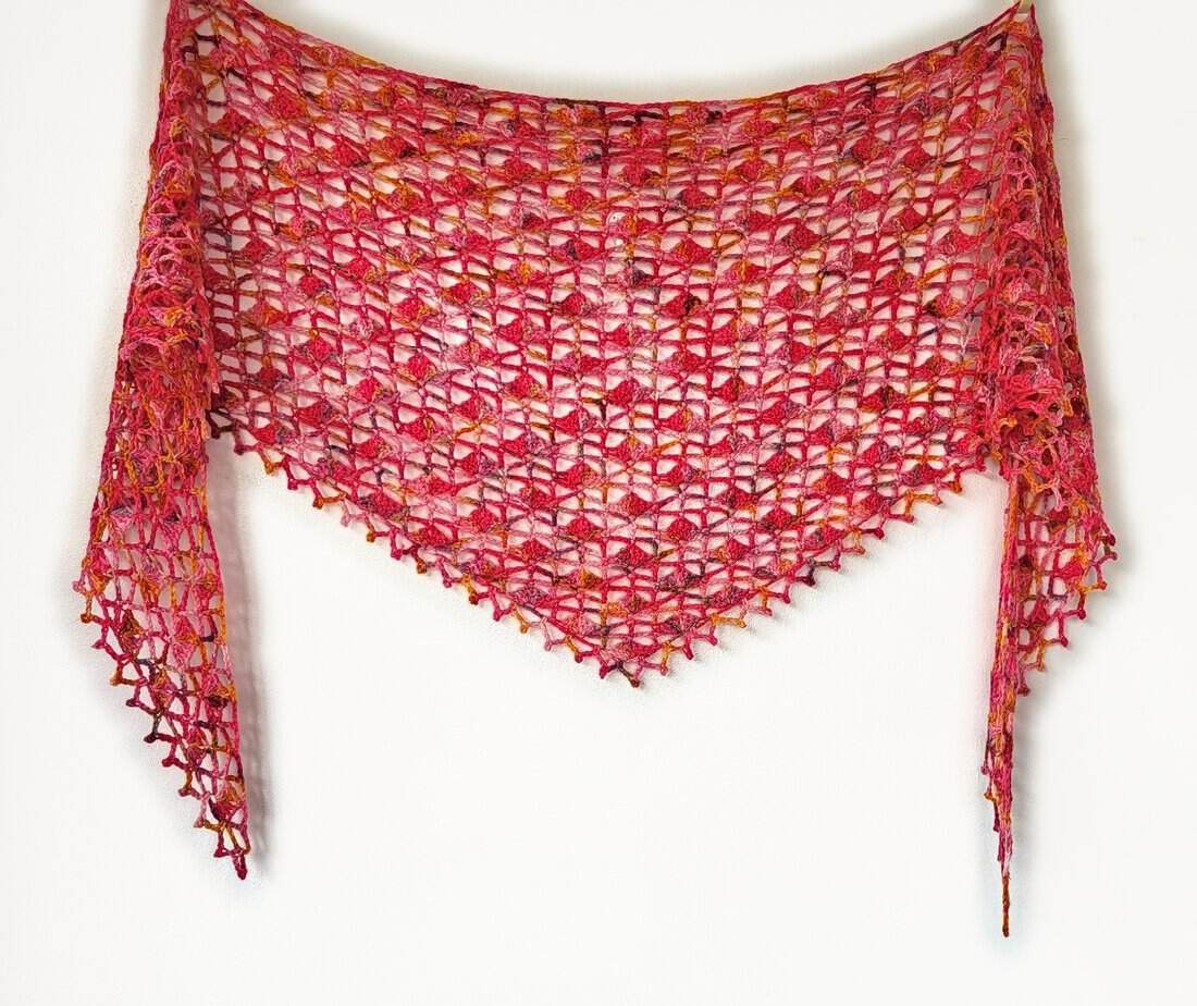 The Rosehip shawl, spread wide to show the lacy crochet stitches
