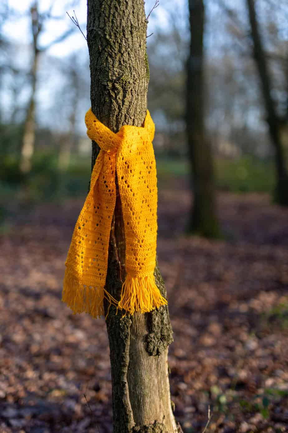 yellow crochet filet scarf on a tree