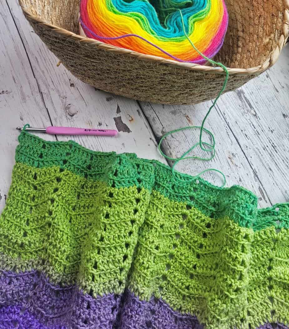 Dapple Crochet Ripple Blanket in progress, shown with hook and working yarn in a basket
