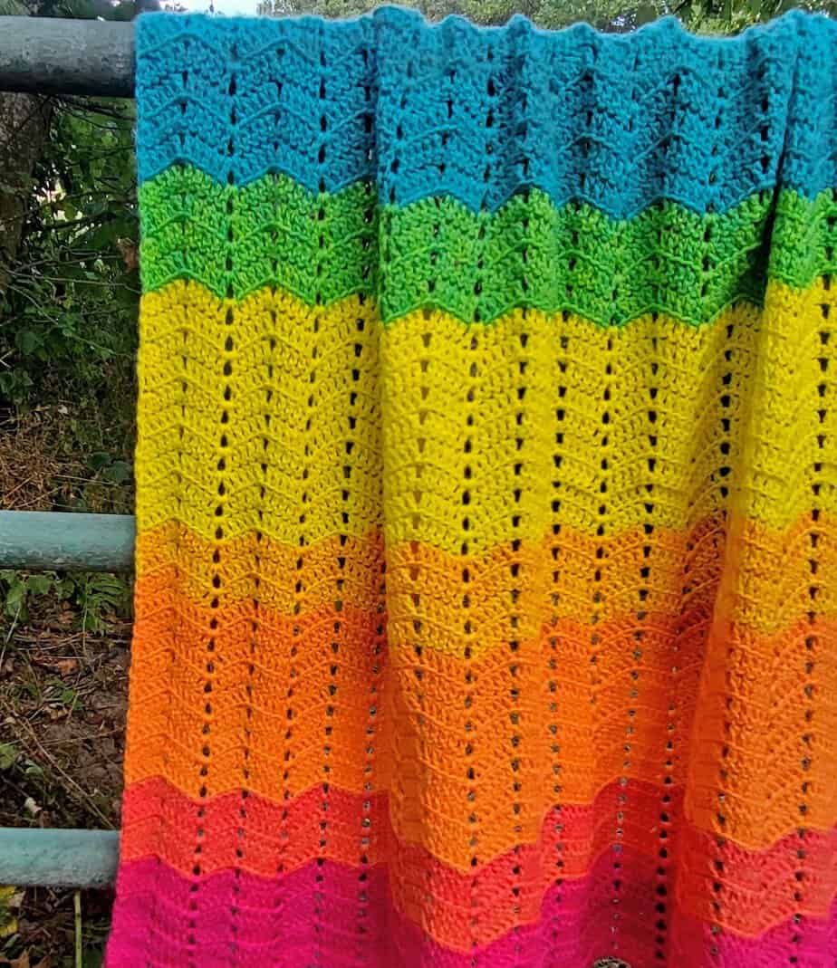 The Dapple Ripple Baby Blanket hanging over a metal fence