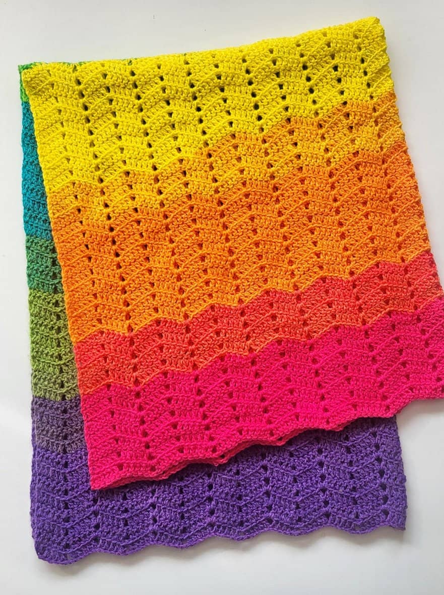 Colorful crochet ripple blanket folded on a white surface